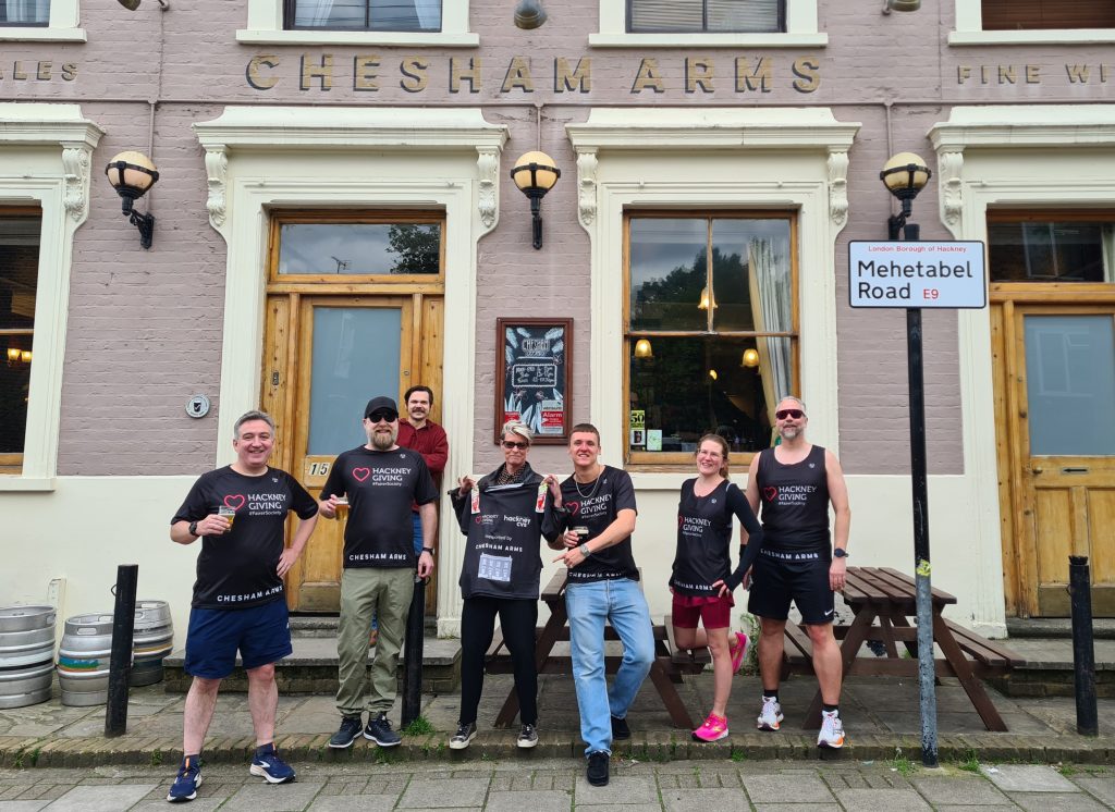 A group of people in Hackney Giving running shirts outside the Chesham Arms