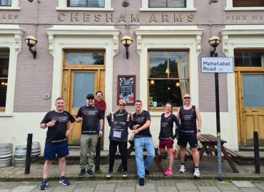 A group of people in Hackney Giving running shirts outside the Chesham Arms